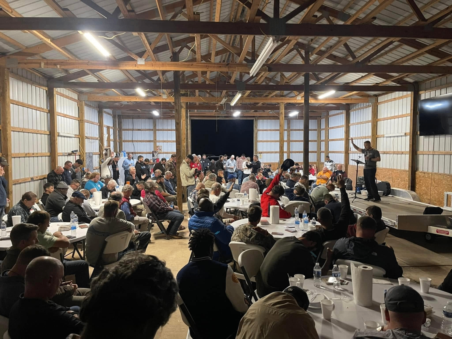 Men praying together inside the packed barn