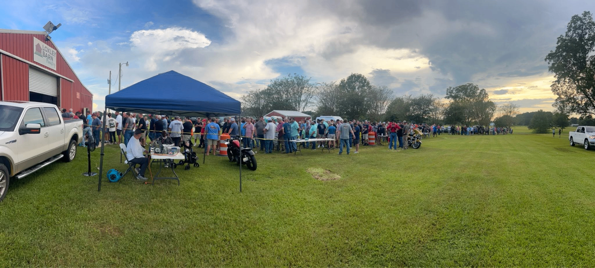 Panoramic view of the line of men gathered outside The Loxley Barn at sunset